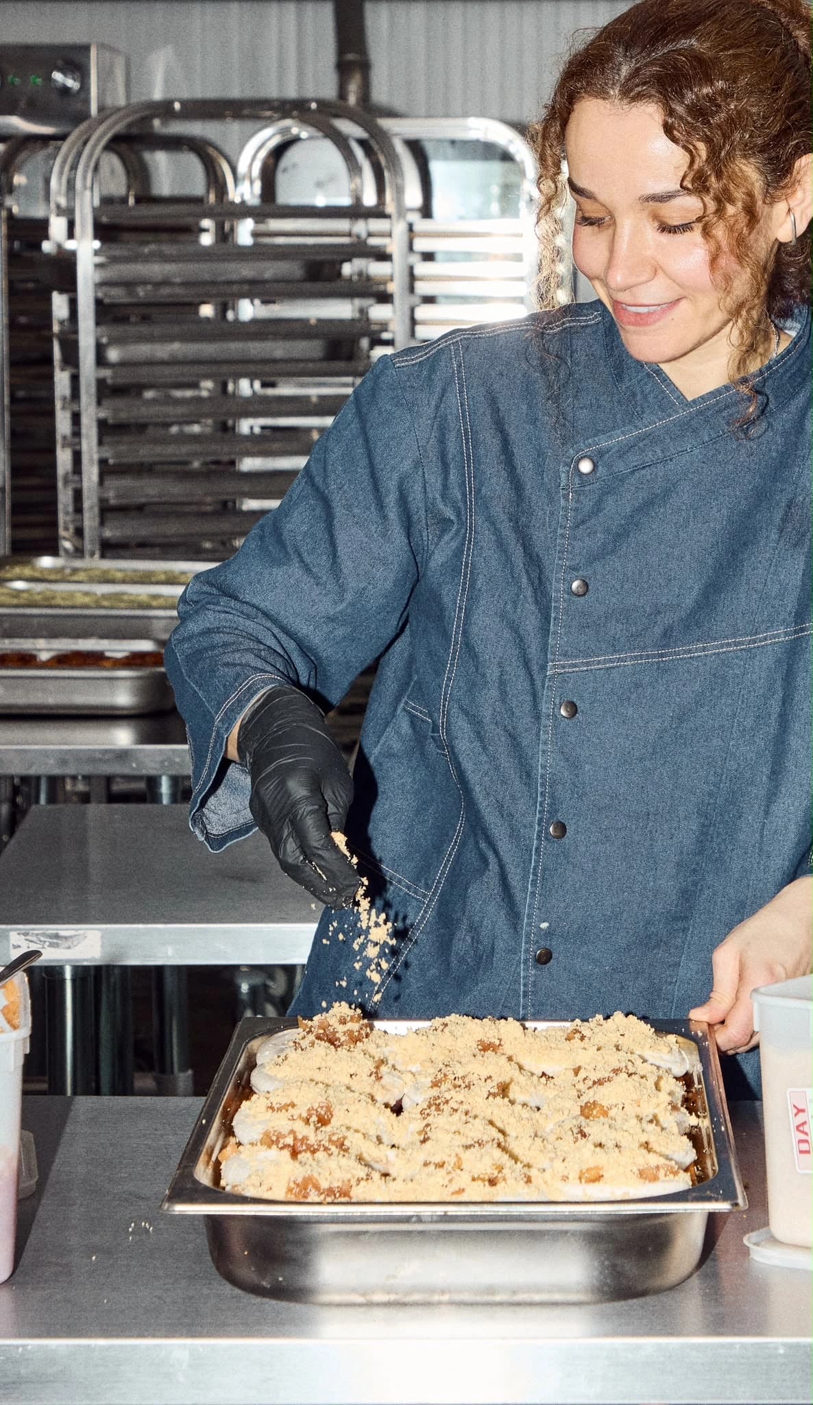 Rise & Bun Soho baker sprinkling crumble over freshly baked buns